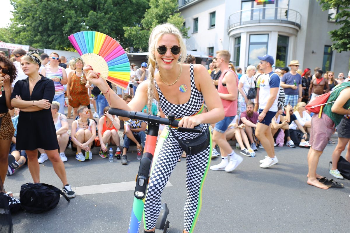 woman in black and white polka dot bikini top and black sunglasses holding multicolored umbrella