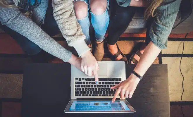 three person pointing the silver laptop computer