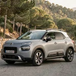 Citroën C3 Aircross garé sur une route de montagne sinueuse entouré de pins et de murs en pierre sèche
