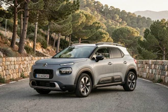 Citroën C3 Aircross garé sur une route de montagne sinueuse entouré de pins et de murs en pierre sèche