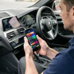 Technicien utilisant une application de diagnostic BMW sur smartphone à l'intérieur d'un véhicule premium