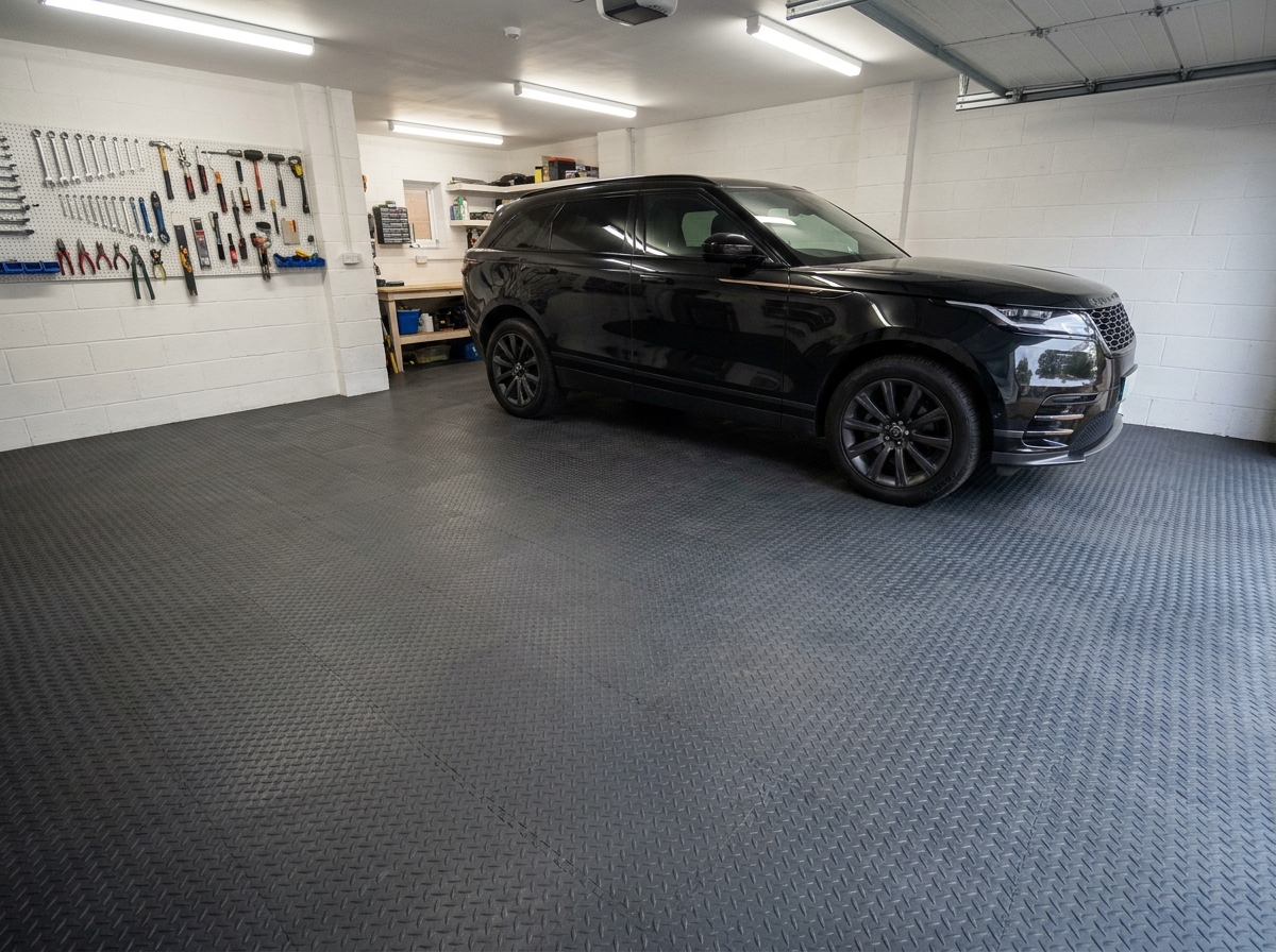 Garage résidentiel avec dalles de sol clipsables grises installées sous un SUV noir, vue d'ensemble