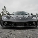 Koenigsegg Agera R noir carbone garé sur route ouverte avec paysage scandinave en arrière-plan
