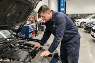 Mécanicien professionnel inspectant le moteur d'une berline dans un garage automobile moderne en Île-de-France