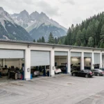 Vue d'ensemble d'un garage automobile professionnel dans le Doubs avec les montagnes du Jura en arrière-plan