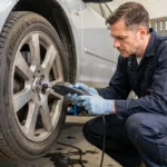 Technicien automobile testant un capteur ABS sur la roue avant d'une berline avec un scanner OBD dans un garage professionnel